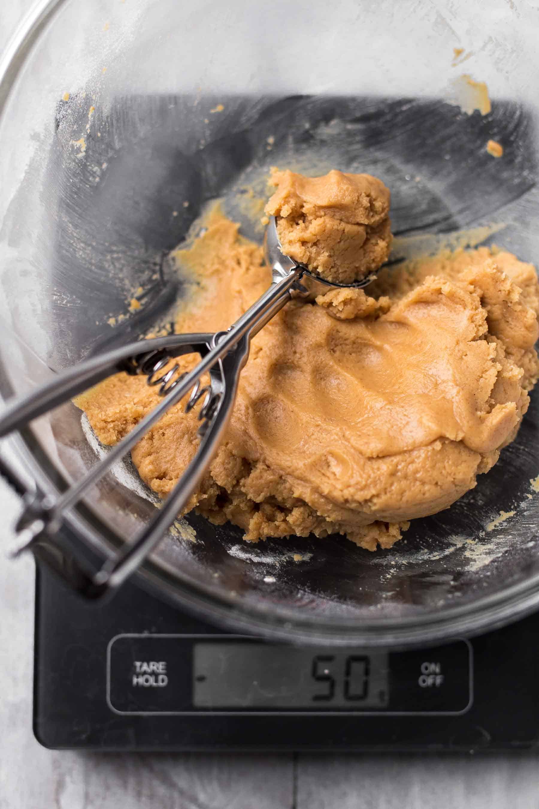 cookie dough in bowl with an ice cream scoop sitting on a kitchen scale