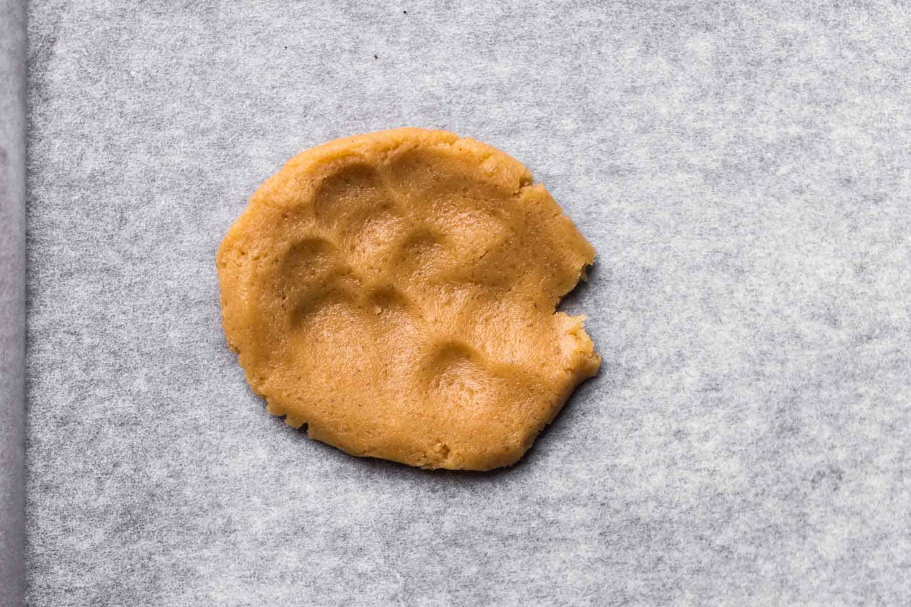 cookie dough piece shaped into a disc on baking paper