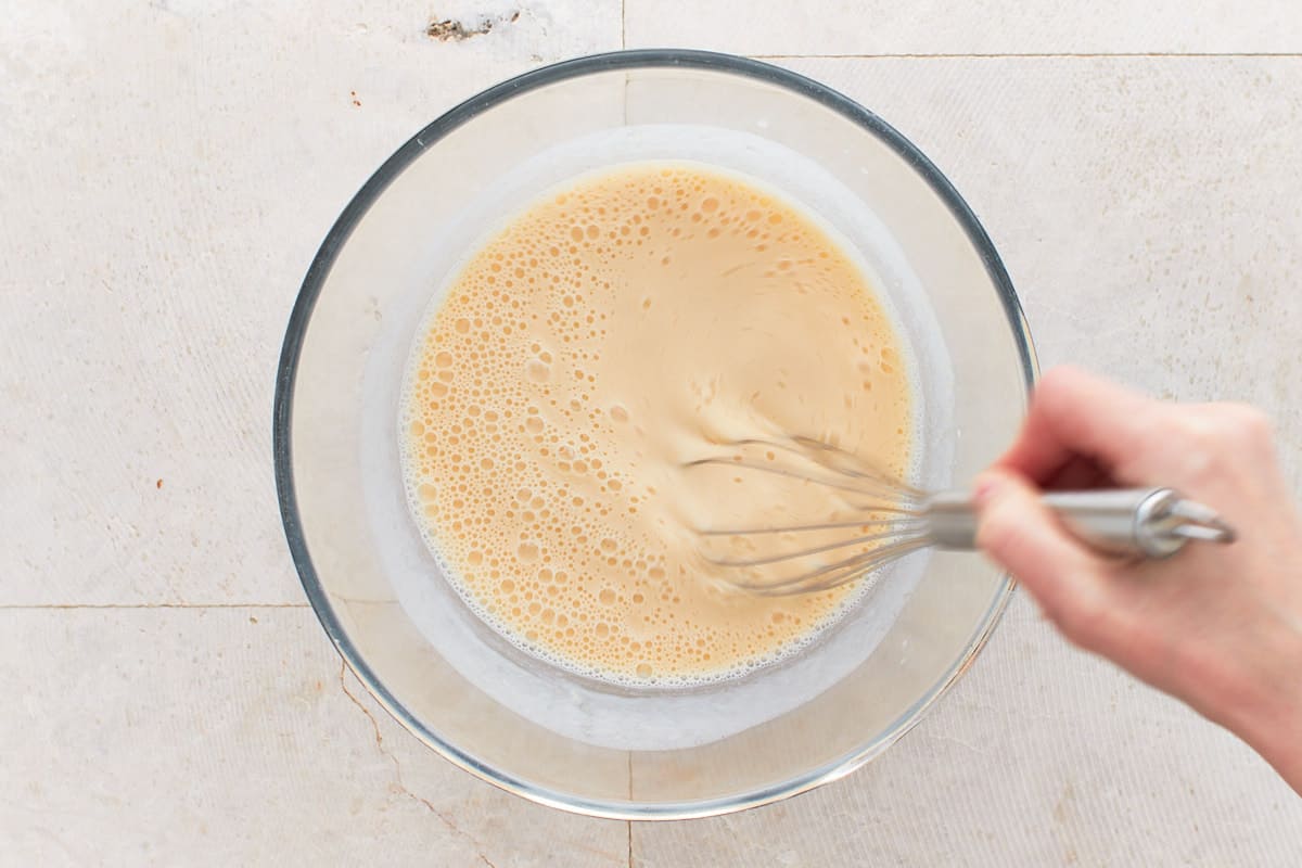 Whisking buttermilk, eggs, maple syrup, and vanilla in a bowl