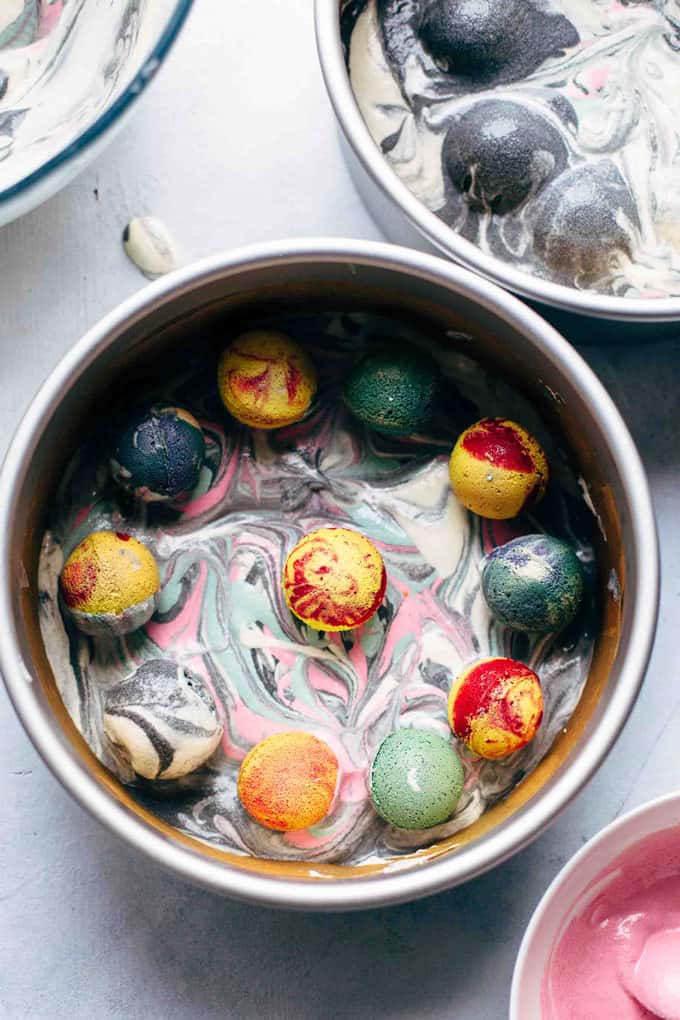 Baked cake pop planets in baking pan on top of unbaked colored cake batter