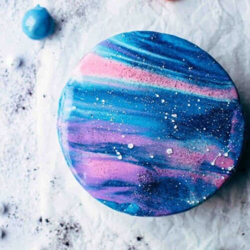 Galaxy cake with blue, teal, pink, and white mirror glaze.