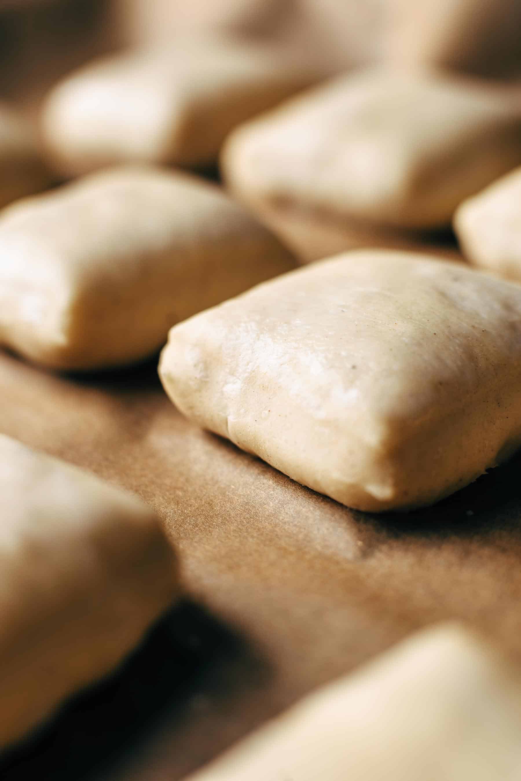 Proofed pieces of yeast dough on a parchment paper layered baking sheet
