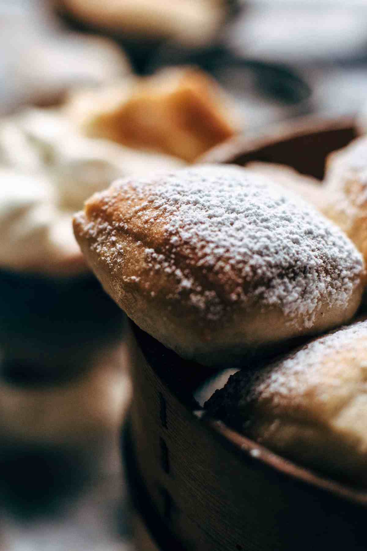 A wooden tray full of a half dozen baked beignets