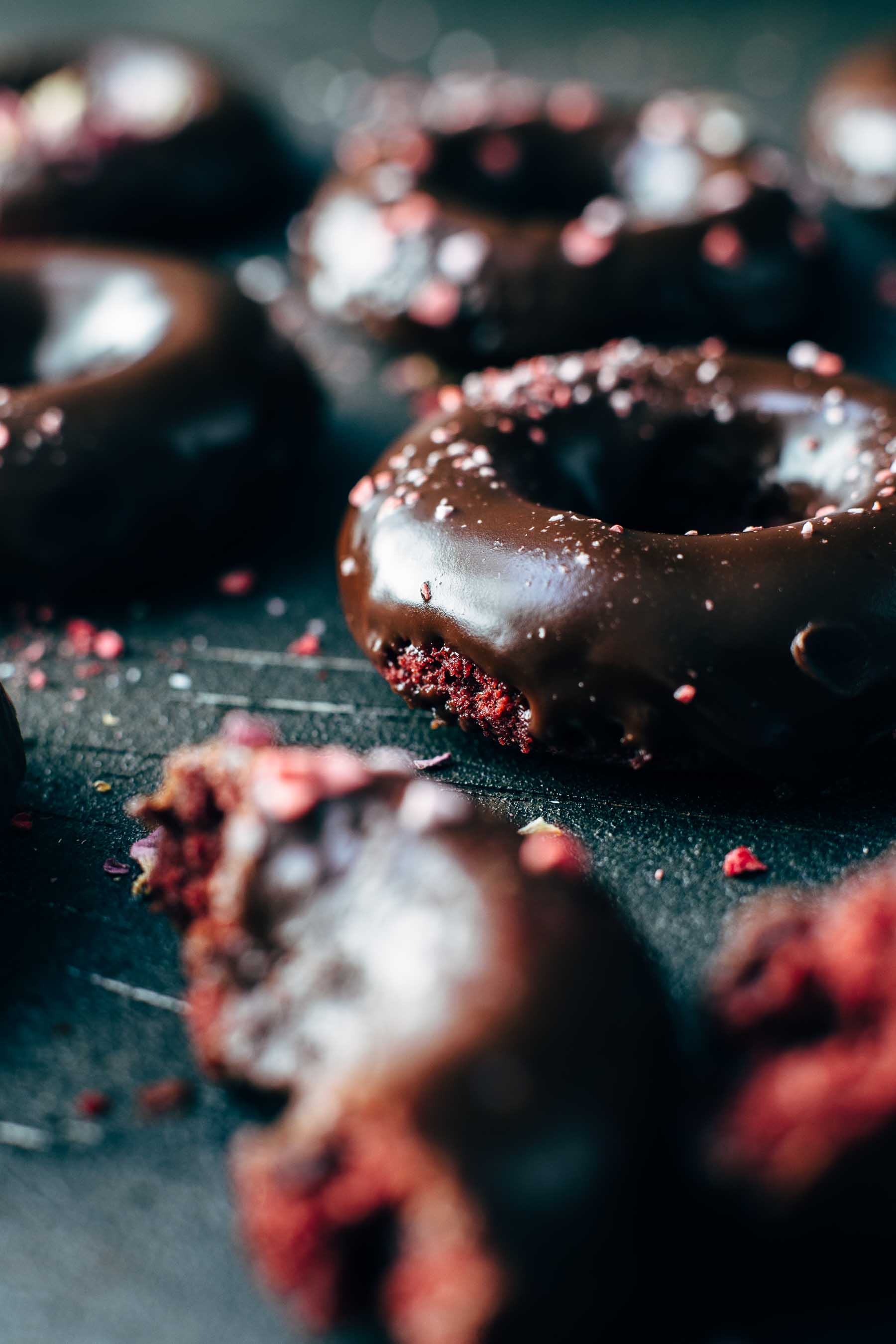 Red colored cake donuts glazed with chocolate on a dark table