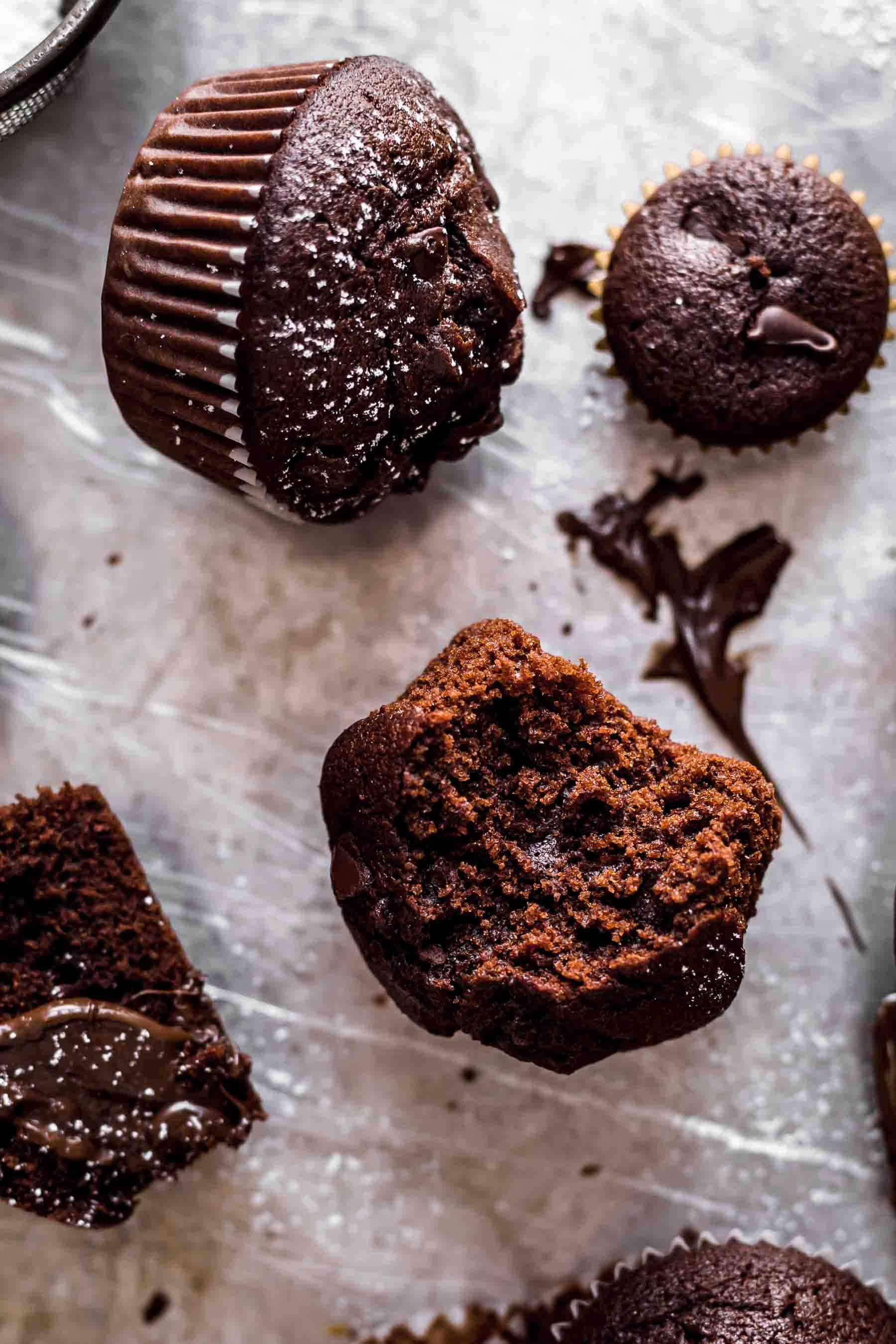 close up of three chocolate muffins, one being half eaten