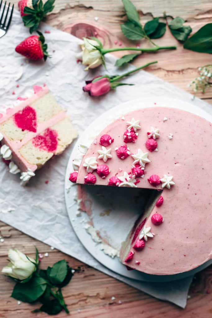 Top down view of a sliced vanilla strawberry cake with flower decoration