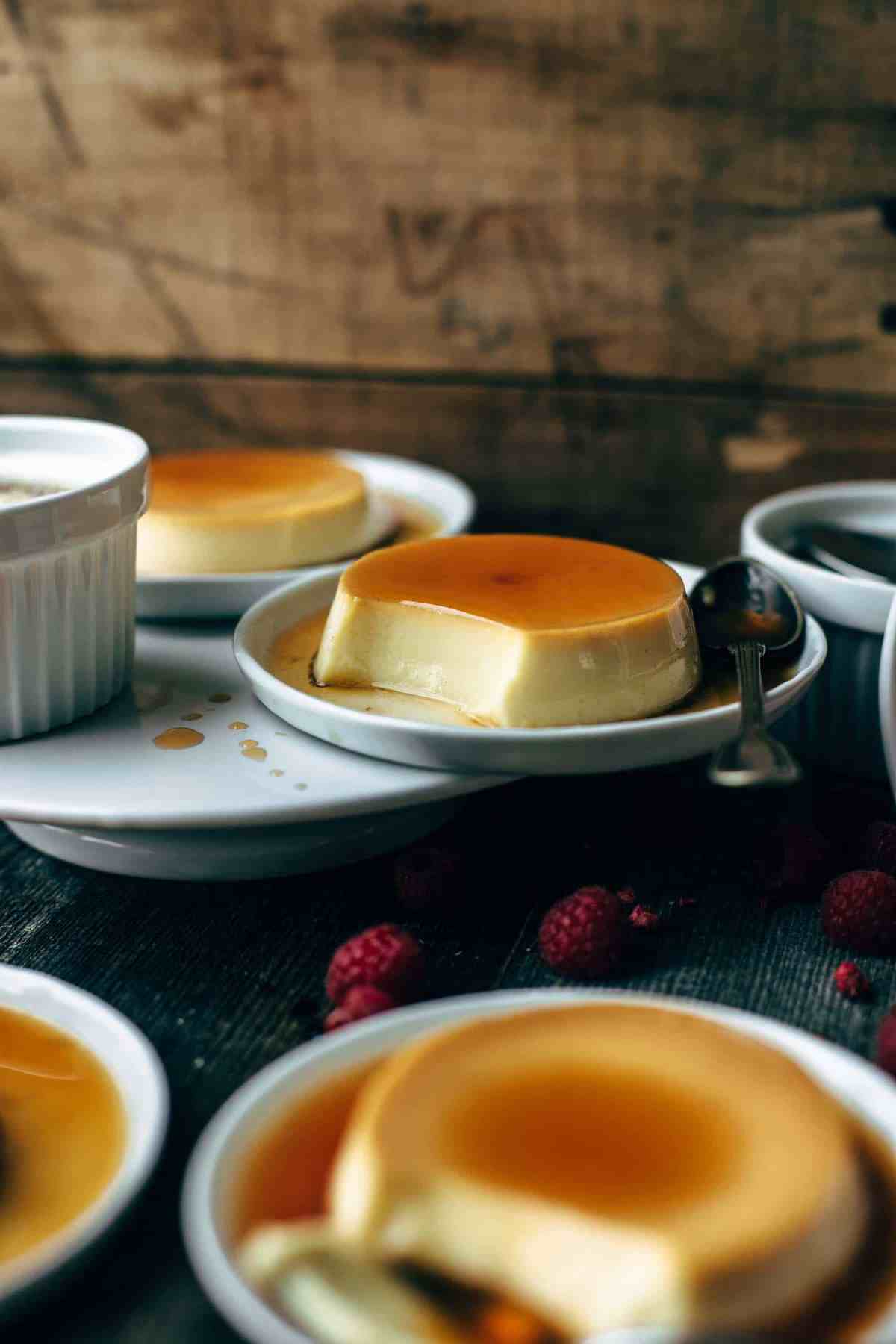 three dessert plates with flan and thin sugar syrup on a wooden table