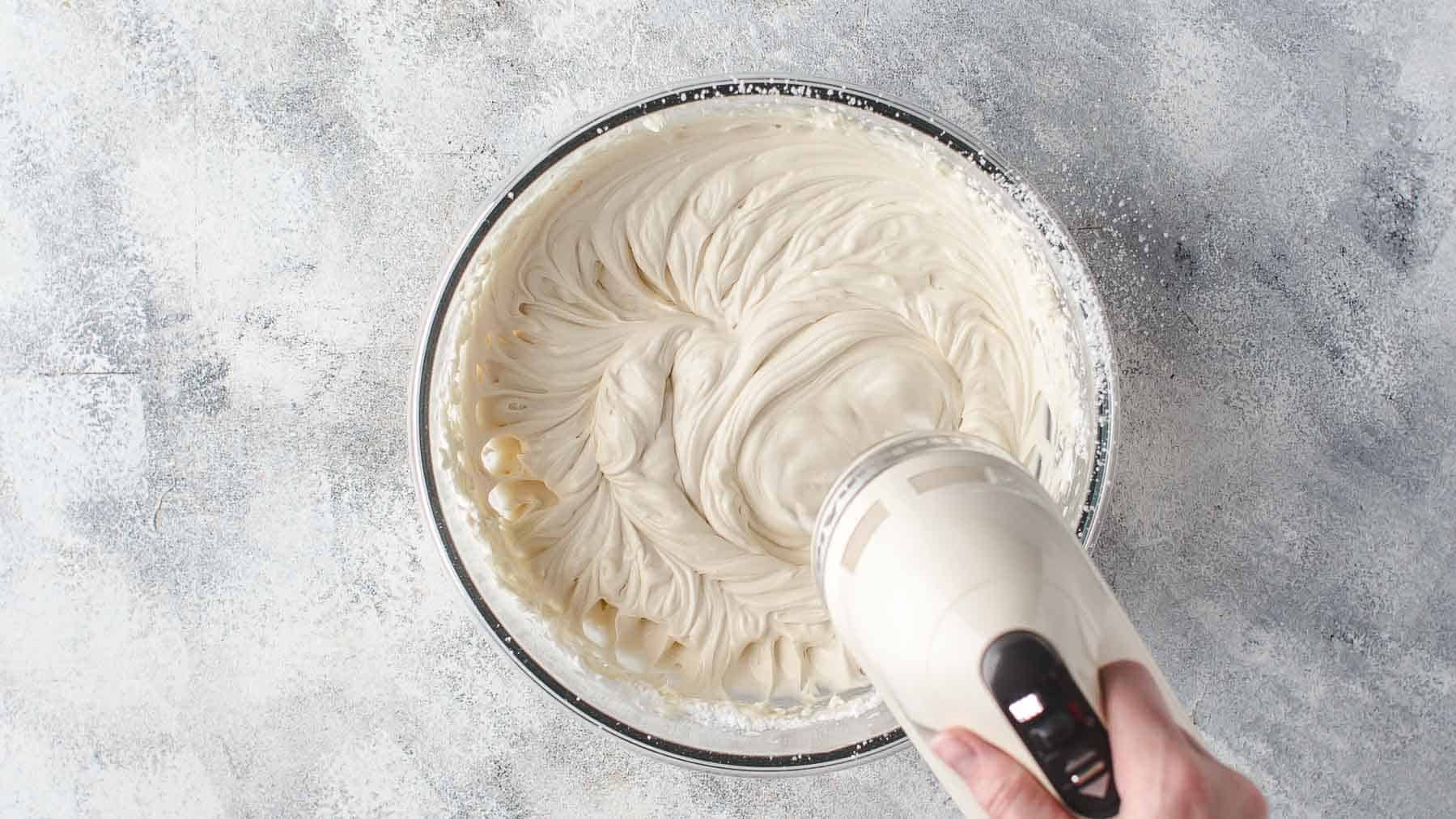 mixing mascarpone frosting in a bowl