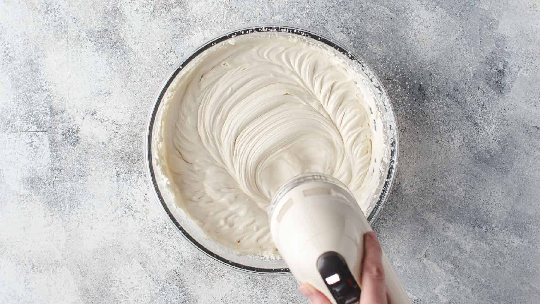 mixing mascarpone frosting and heavy cream in a bowl