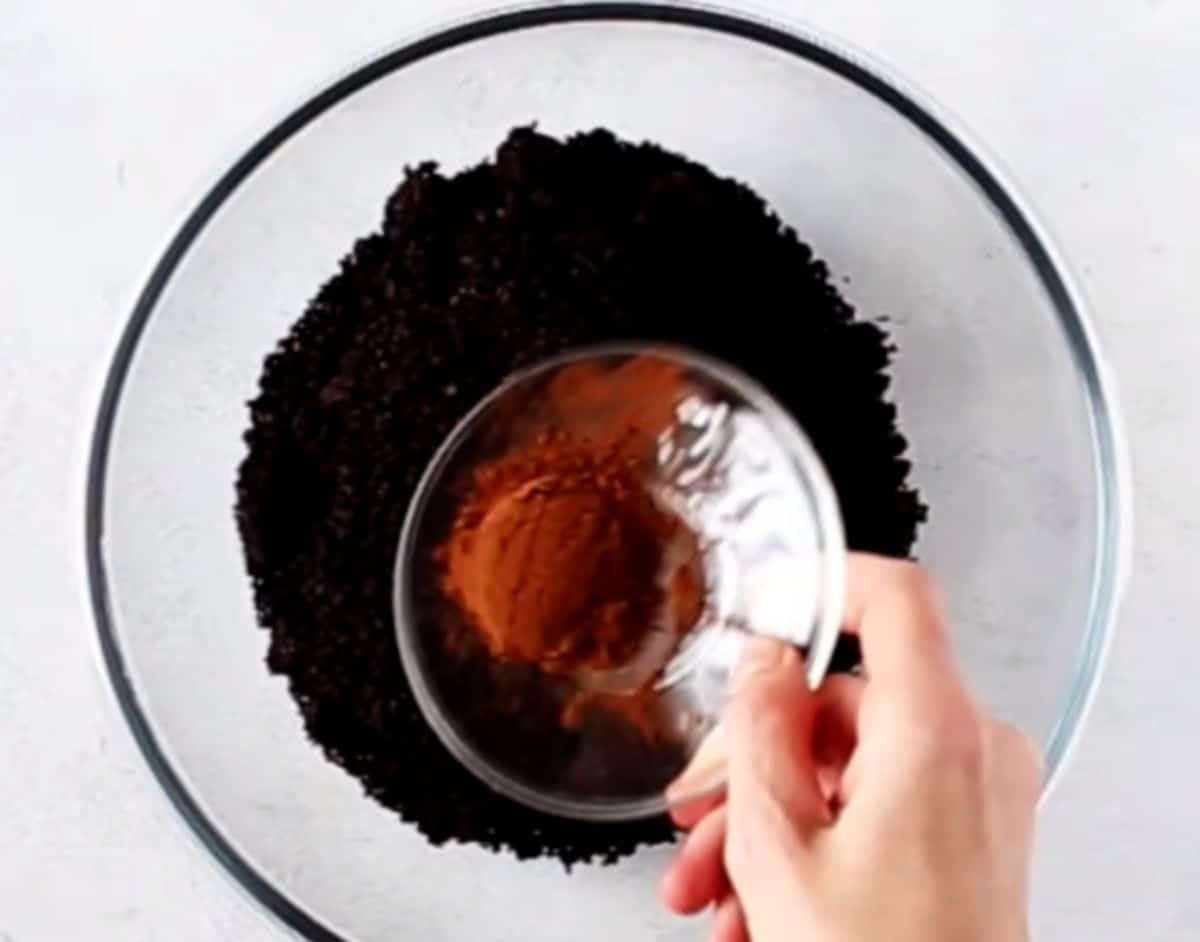 sprinkling cocoa on fine chocolate cookie crumbs 