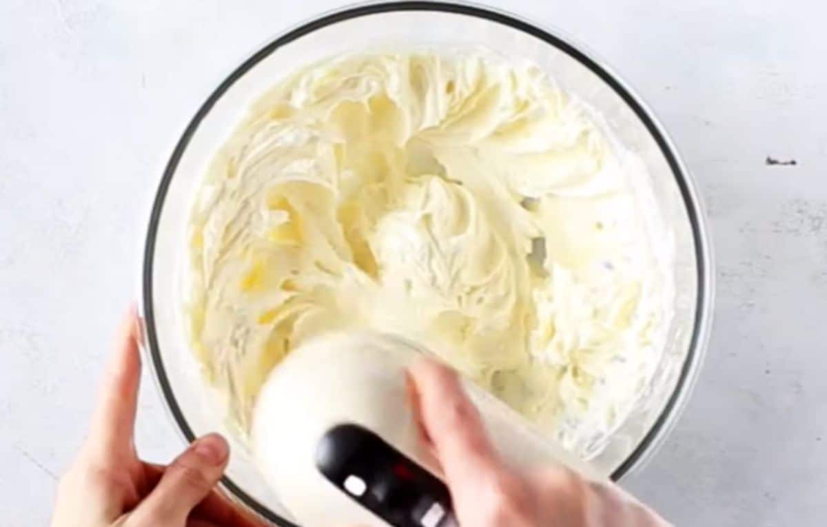 a glass bowl with cream cheese being whisked