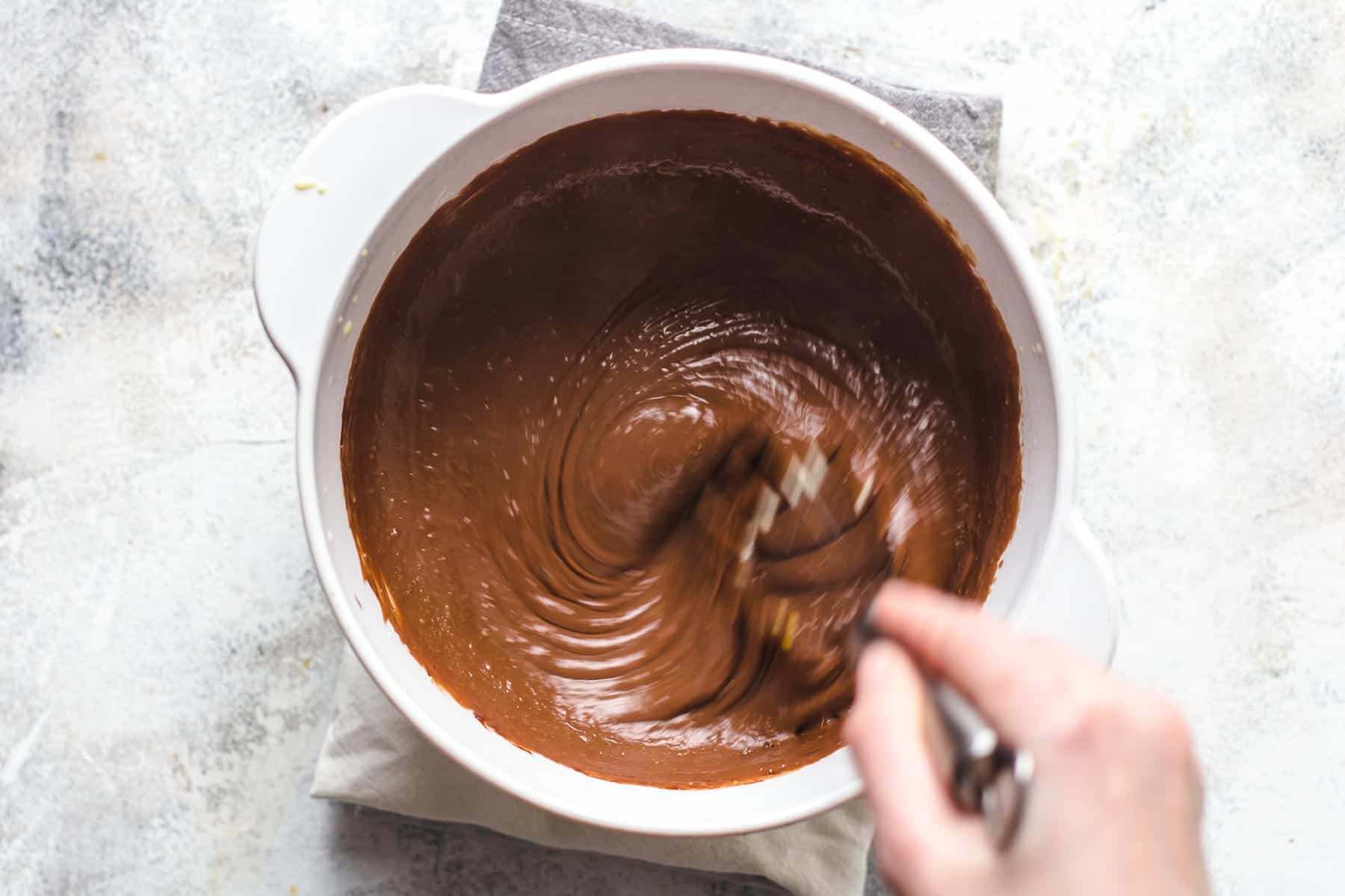 whisking chocolate pastry cream in a white pot
