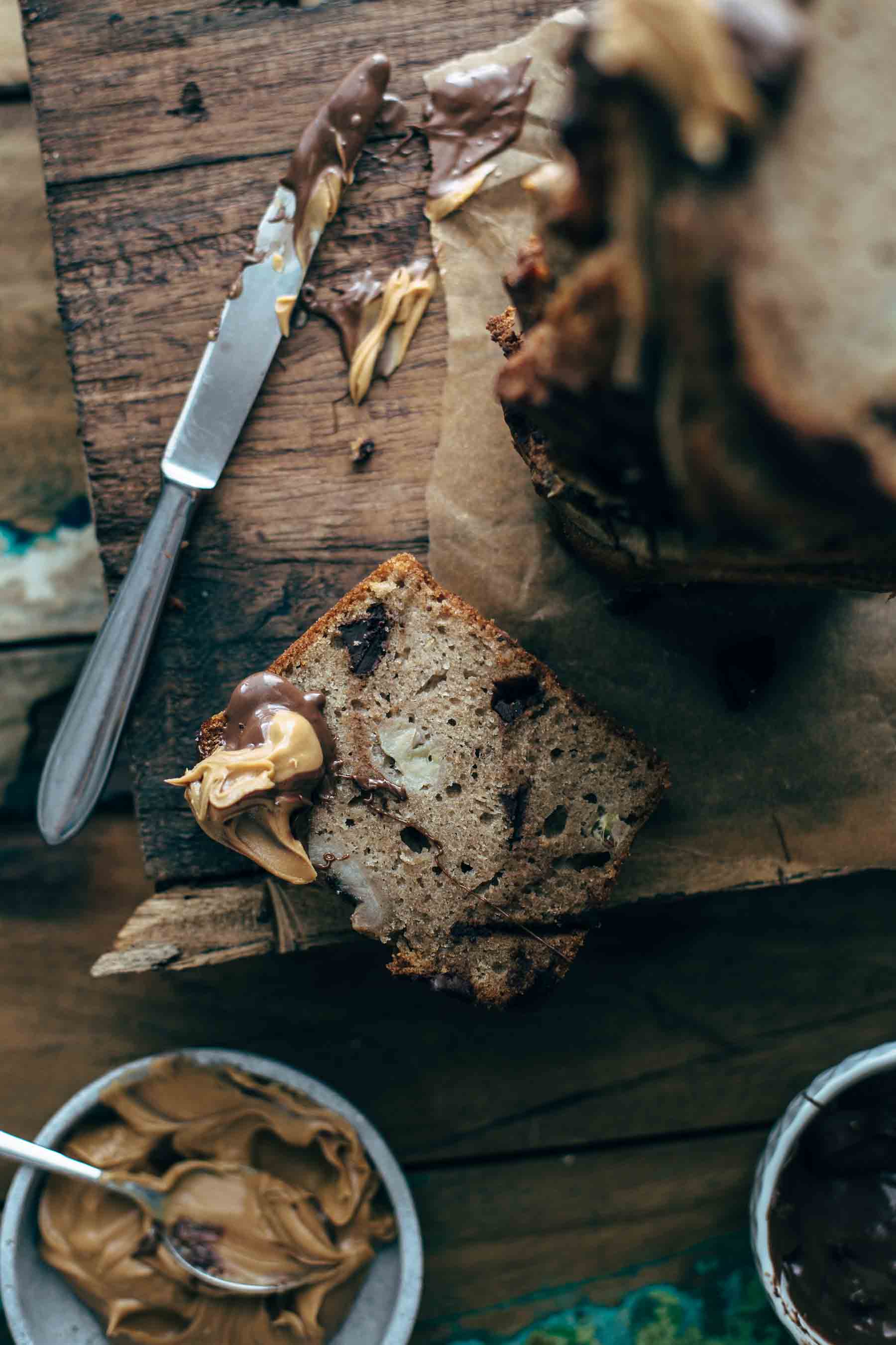 Cut Chocolate Peanut Butter Banana Bread slices on wood with knife