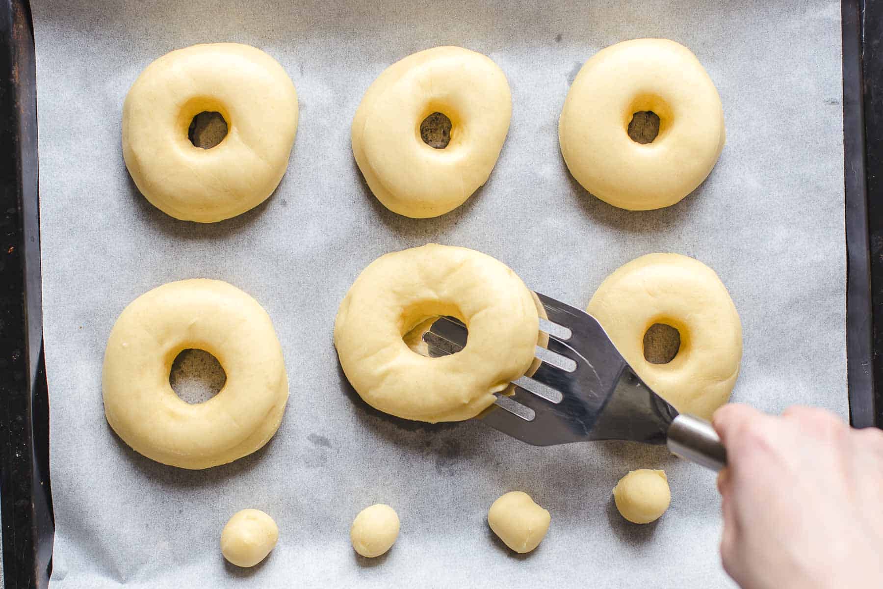 lifting risen yeast dough ring with a spatula