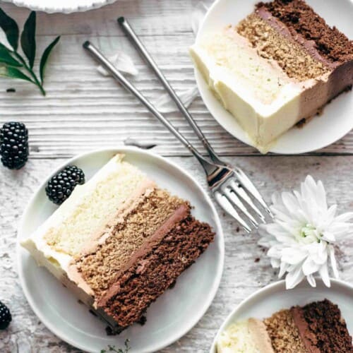 three slices of chocolate layer cake with three different colors of layers on dessert plates