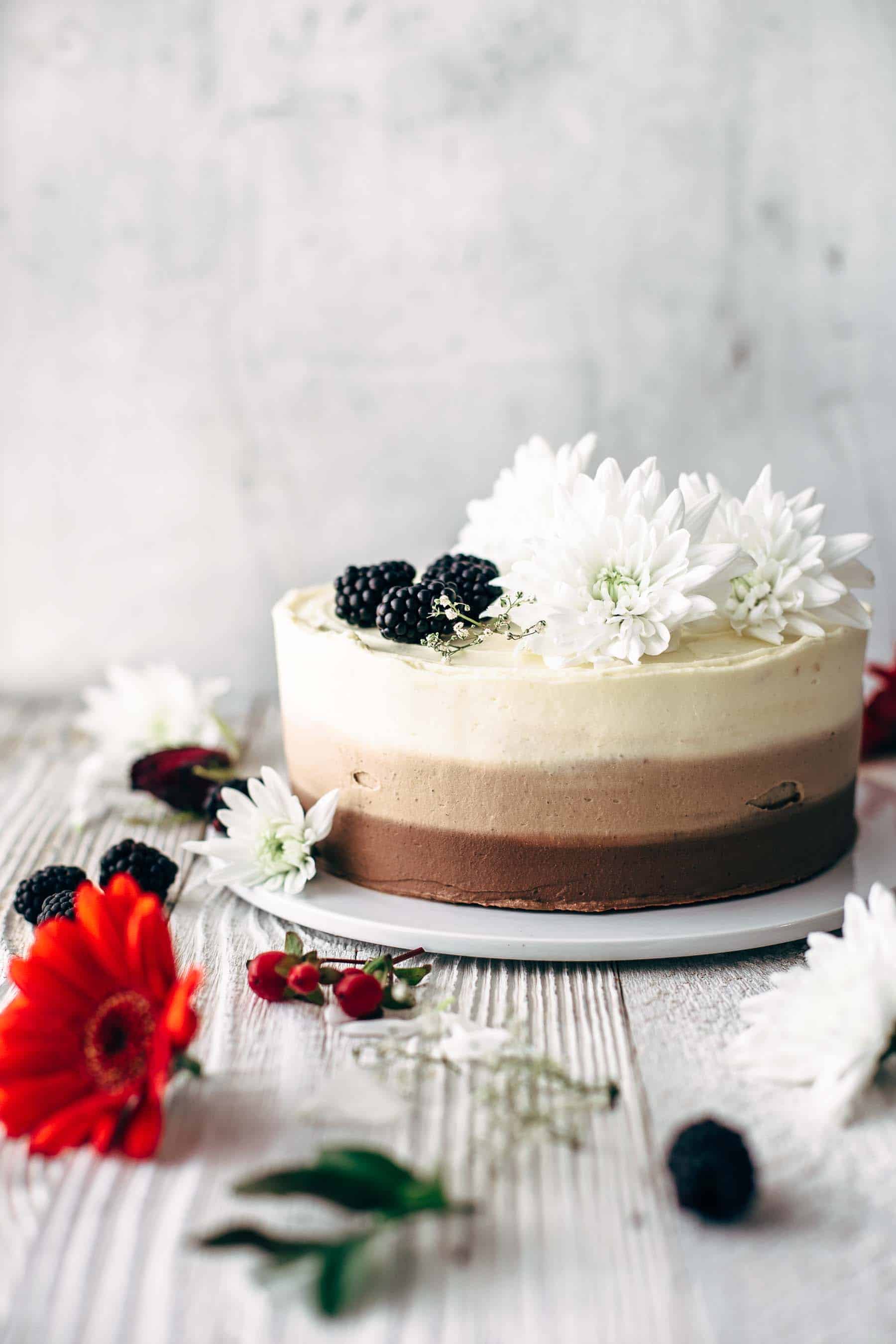 chocolate ombre cake decorated with flowers and berries on a white cake plate