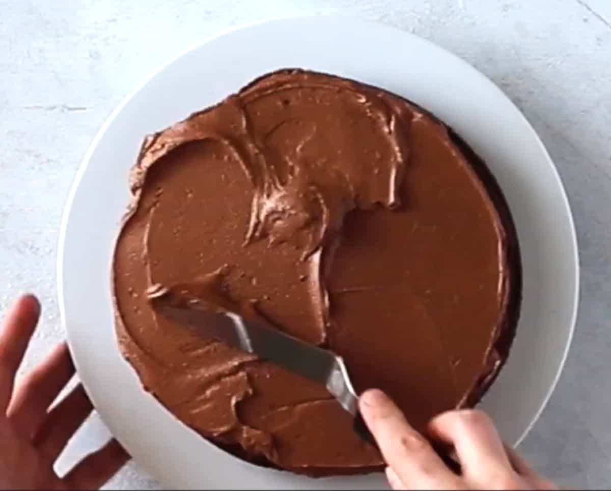 applying chocolate frosting on cake