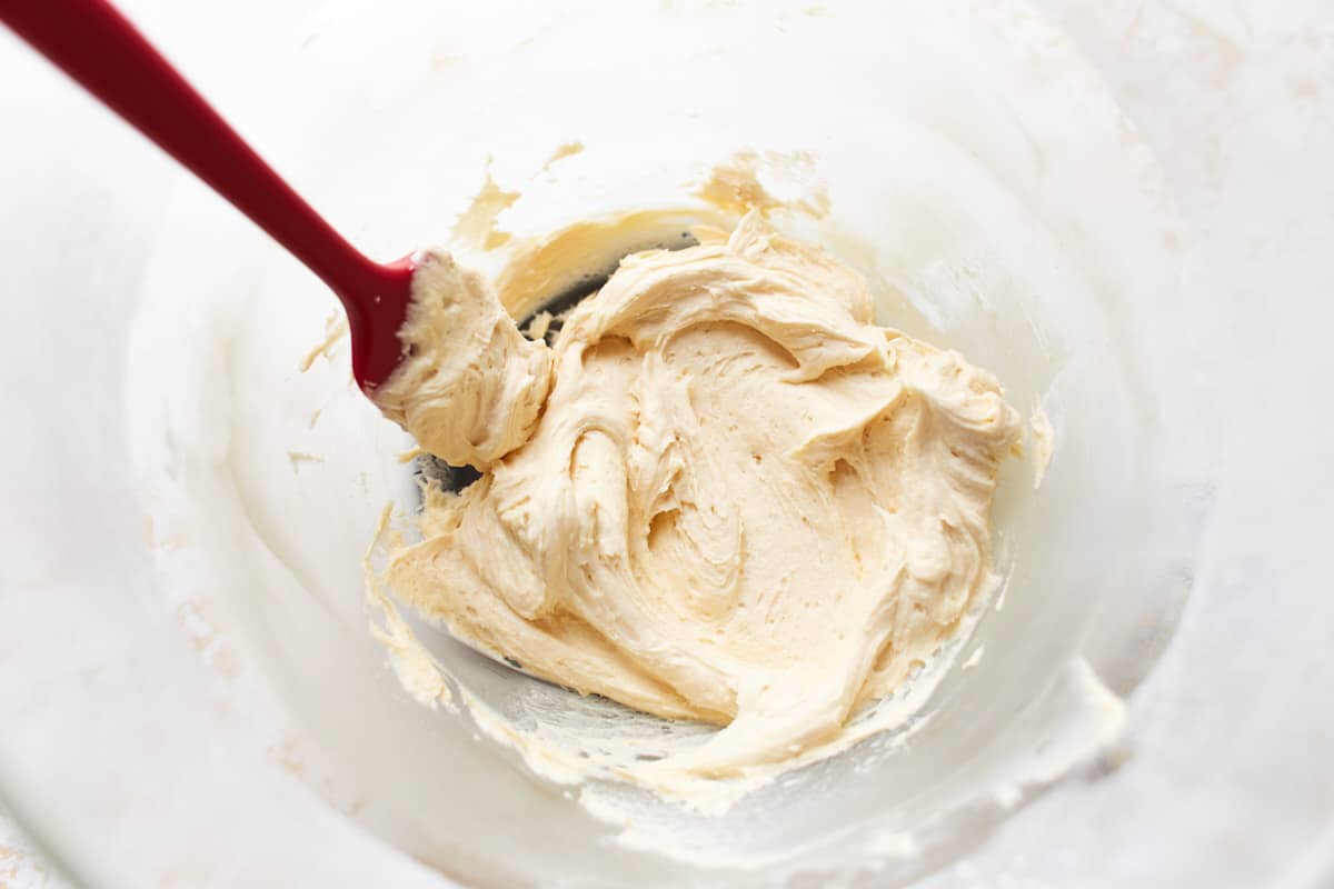 Mixed caramel frosting in a large bowl with a spatula