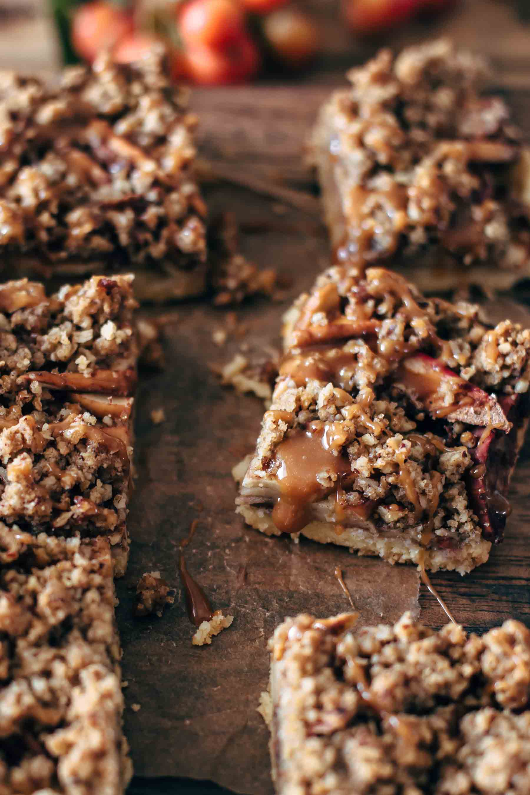 close up of baked shortbread bars topped with apples, nuts, and caramel sauce