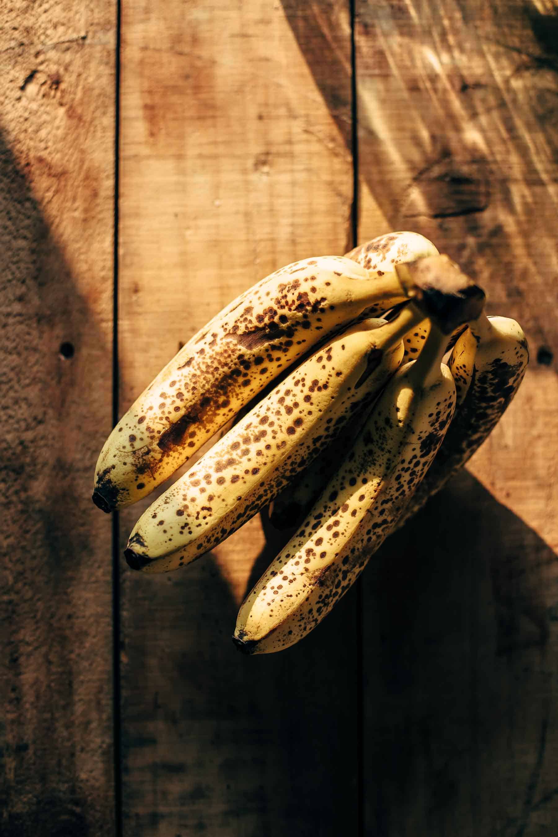 ripe bananas with lots of brown spots on a wooden table