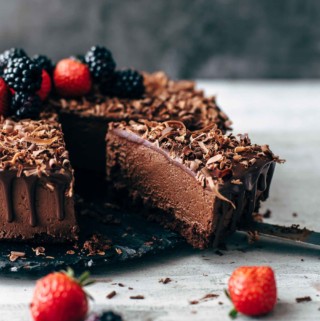 sliced chocolate mousse cake topped with berries, ganache, and chocolate shavings