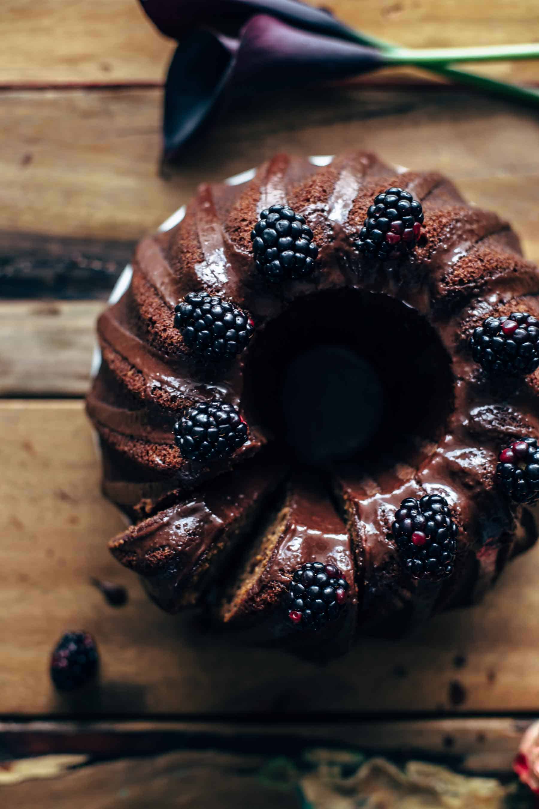Sliced bundt cake with berries on top on a wooden table