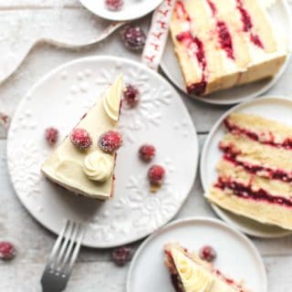 Slices of white cake on dessert plates with topped with sugar coated cranberries