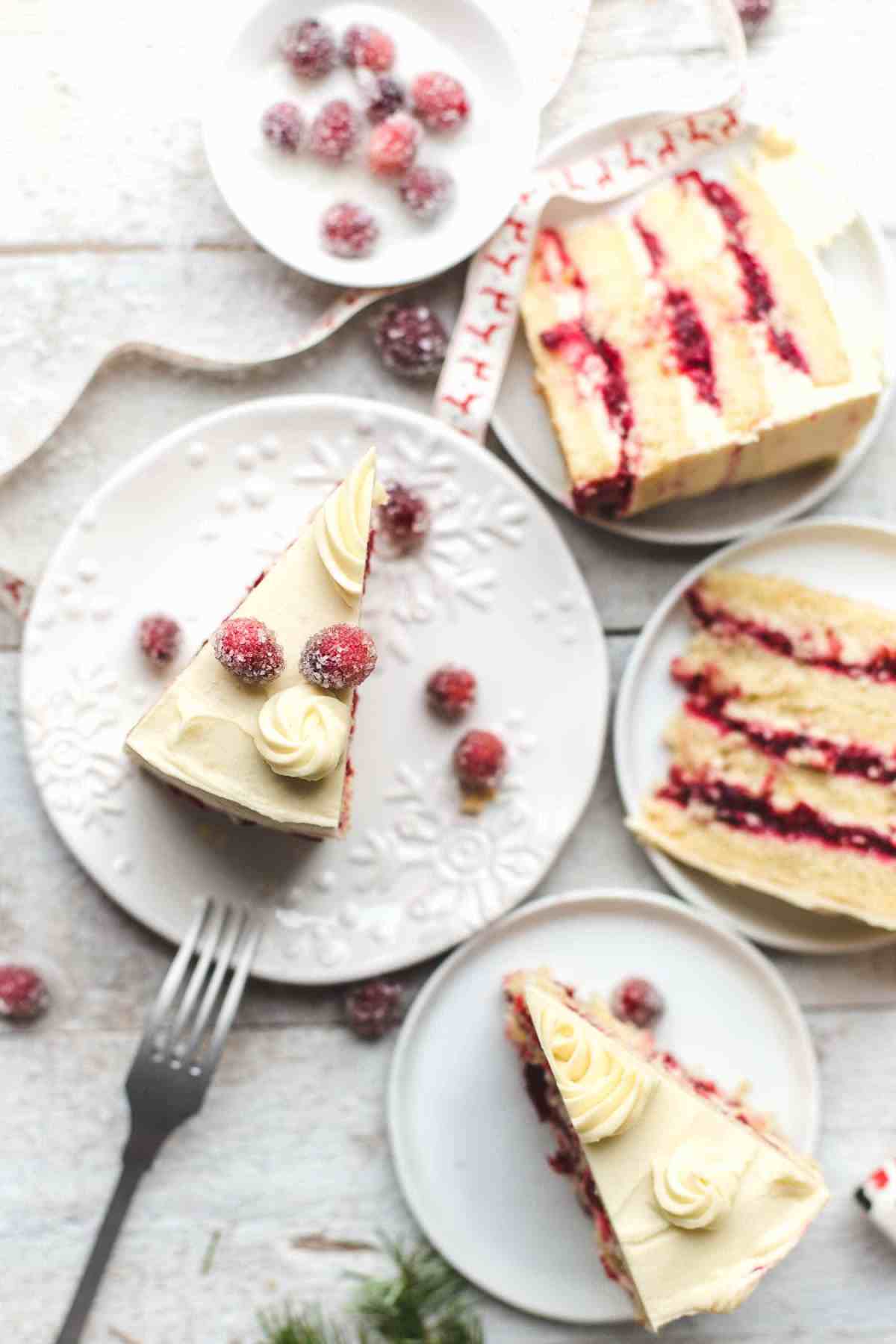 slices of orange layer cake filled with cranberries on white dessert plates