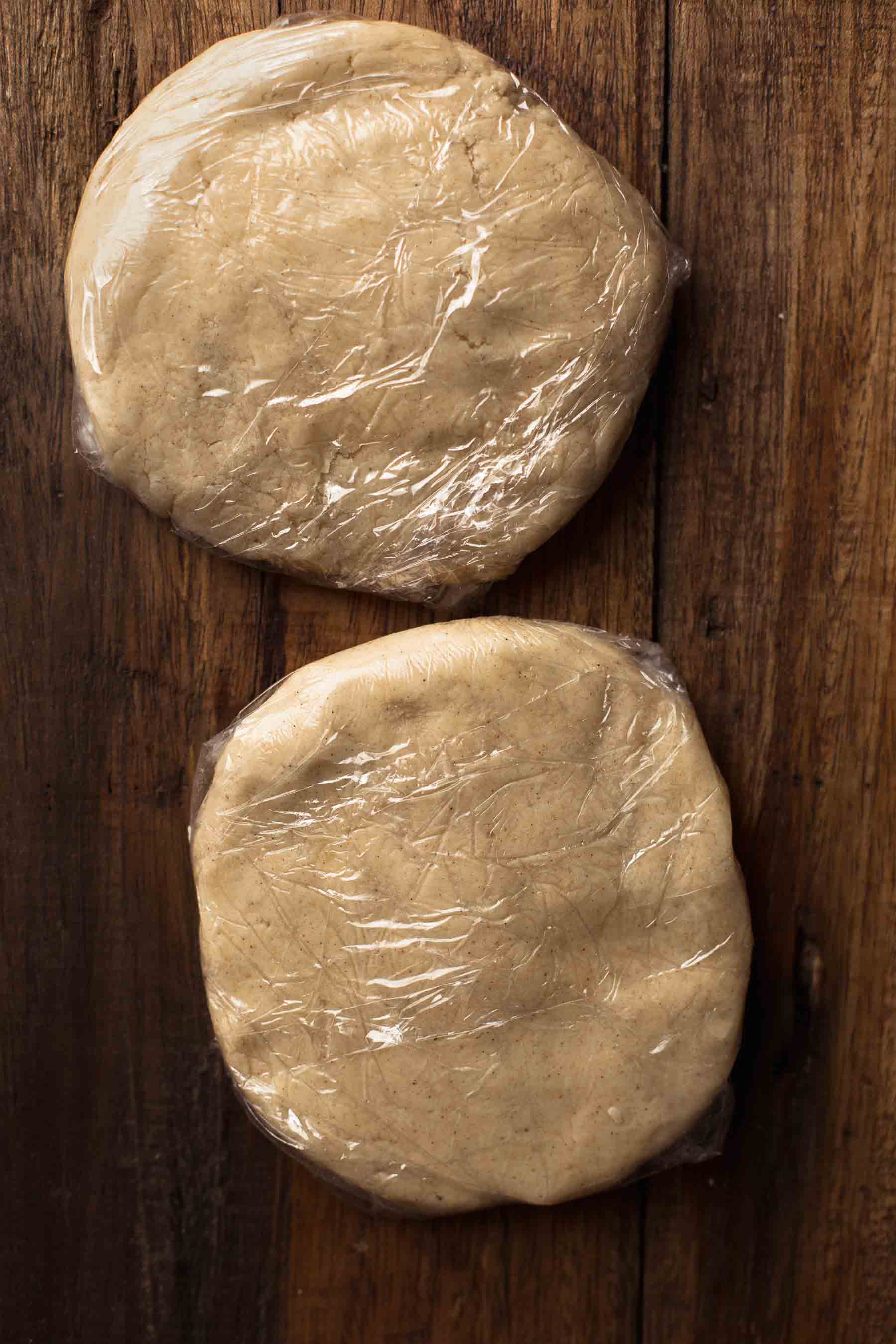 two unbaked cookies dough discs wrapped in plastic wrap