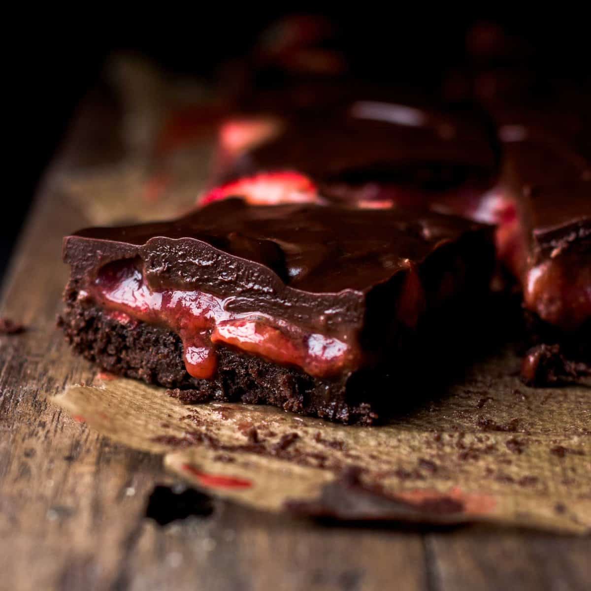 a slice of chocolate covered brownie with oozing strawberry filling