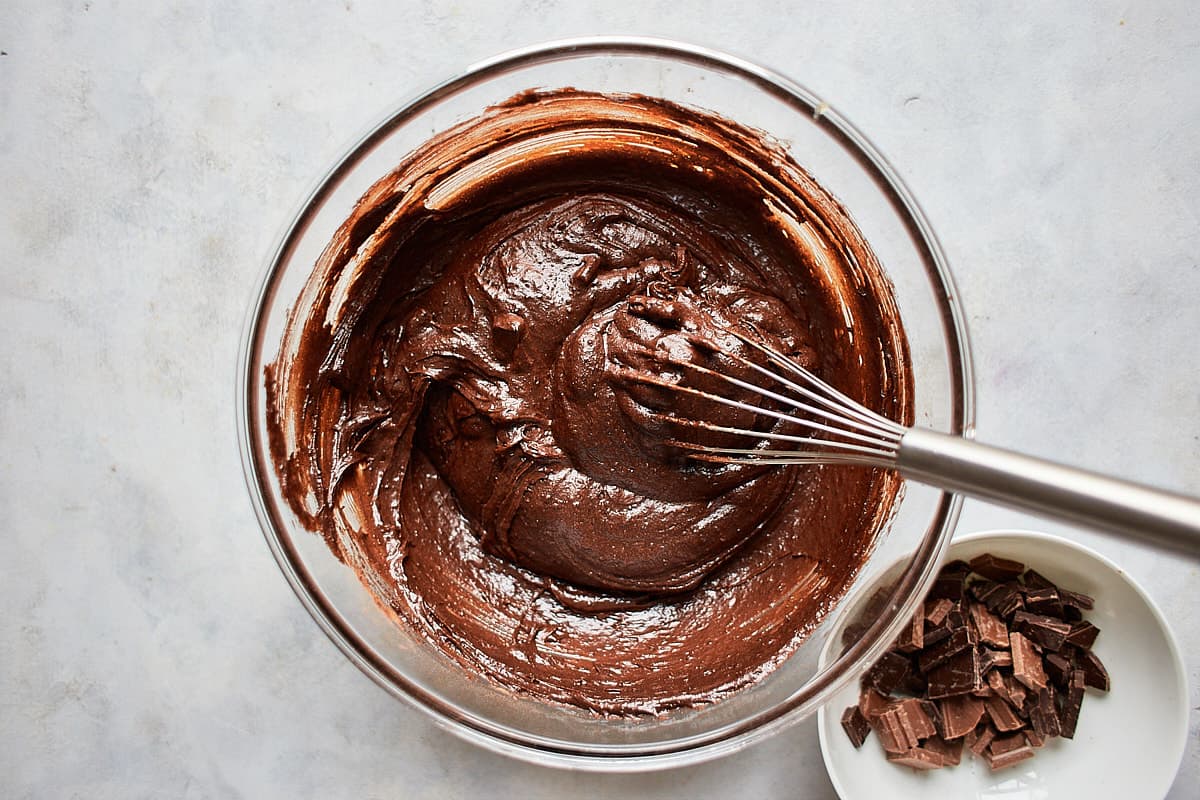 mixed brownie batter in glass bowl with a whisk
