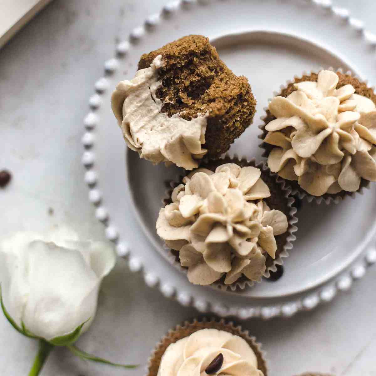 three coffee cupcakes on a white plate with one being half eaten