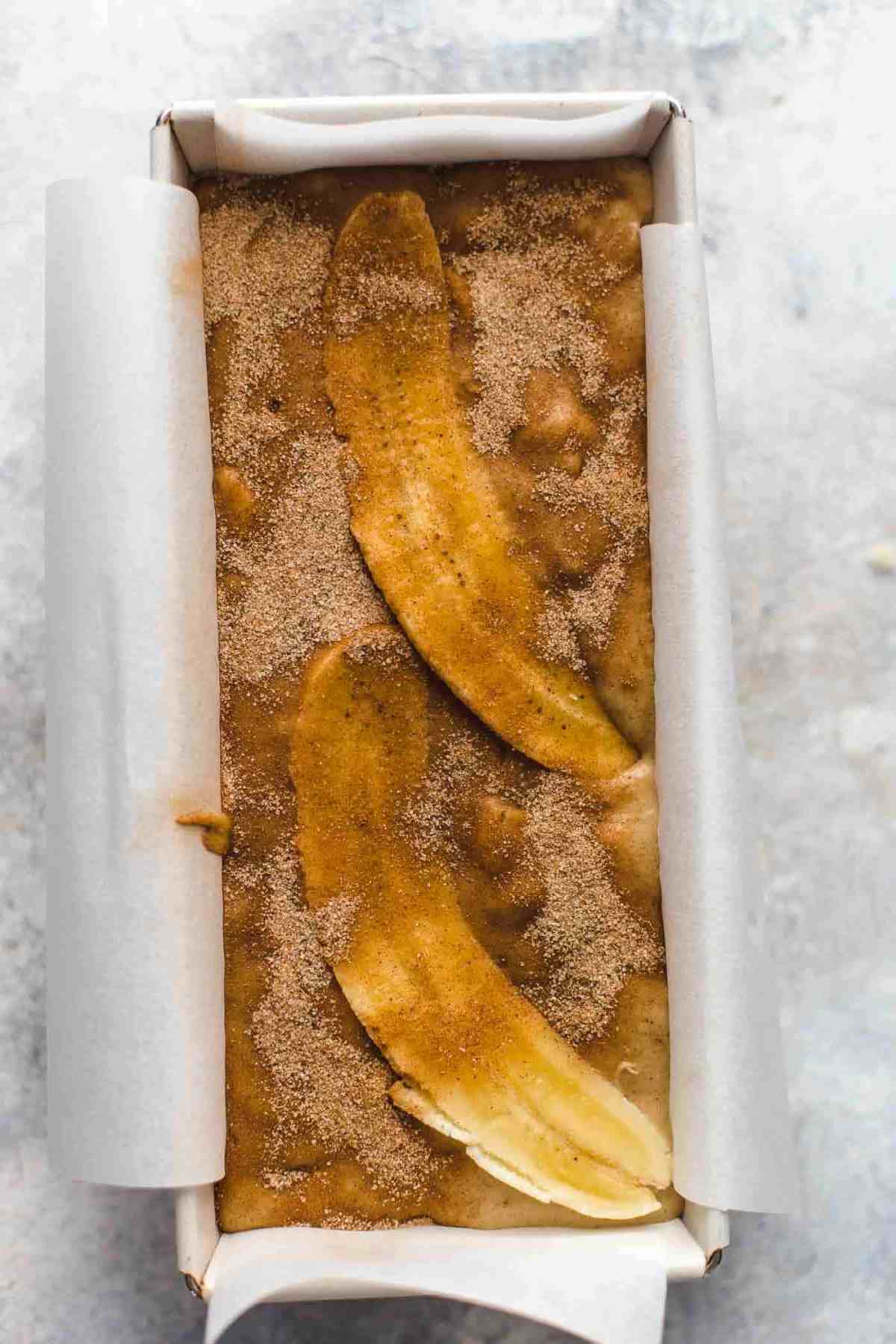 banana bread batter with bananas and sugar on top