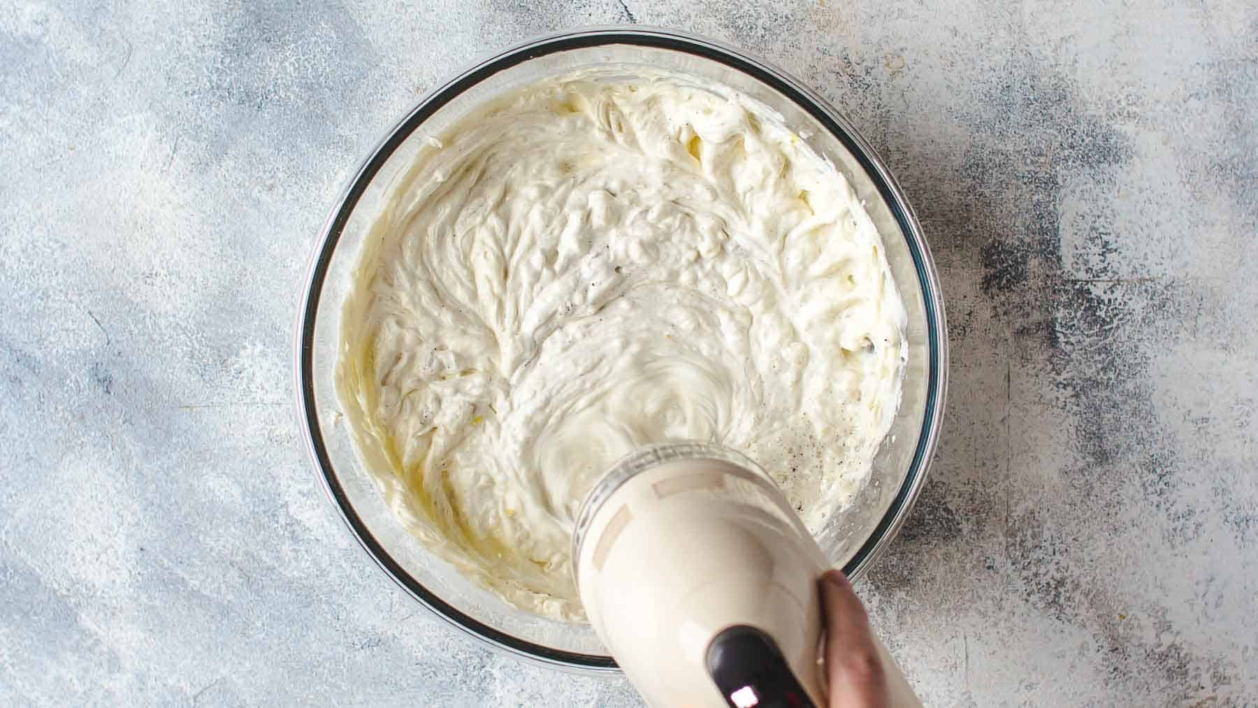 curdled looking cream cheese mixture mixing in a pan