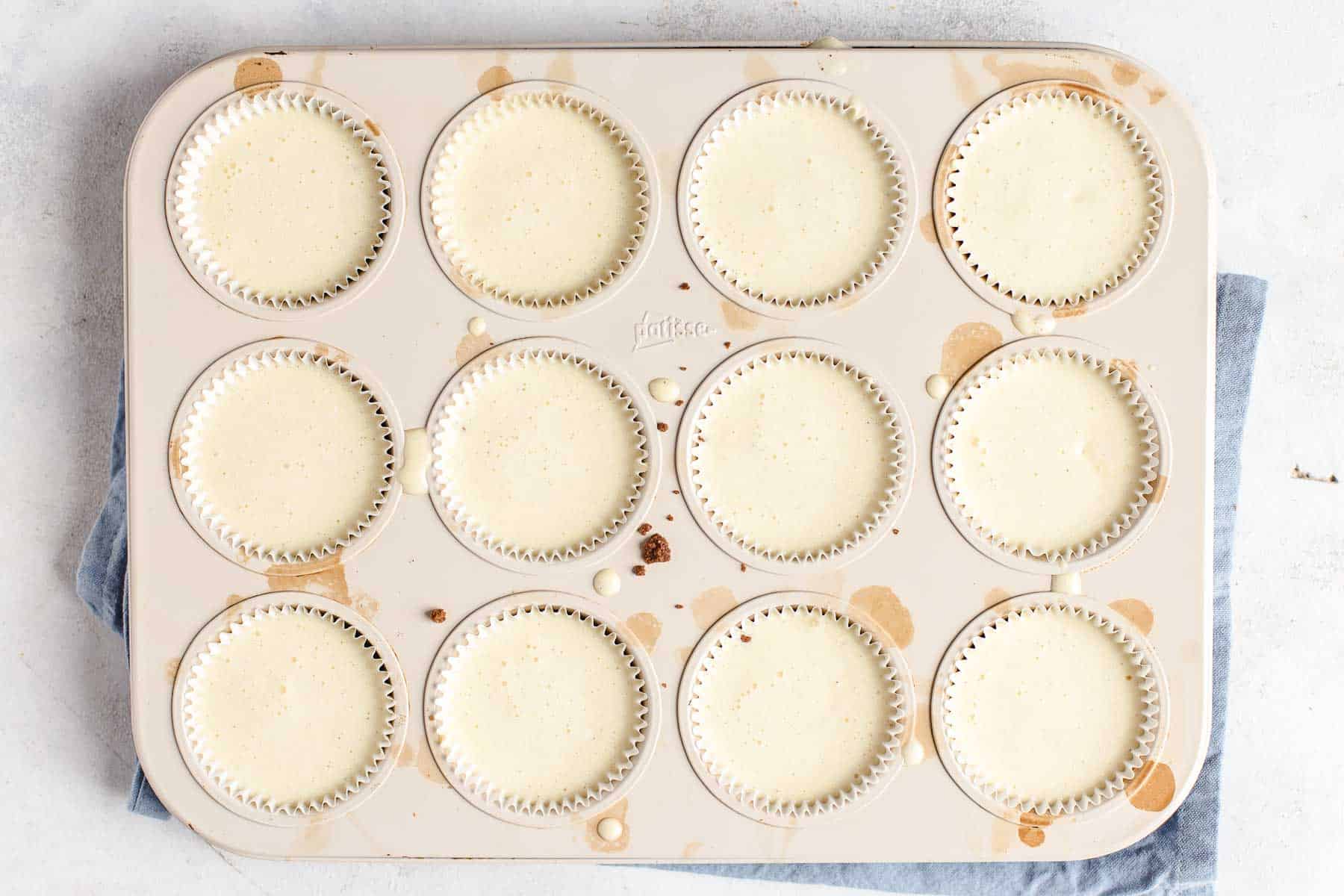 muffin pan filled with cheesecake batter ready to bake