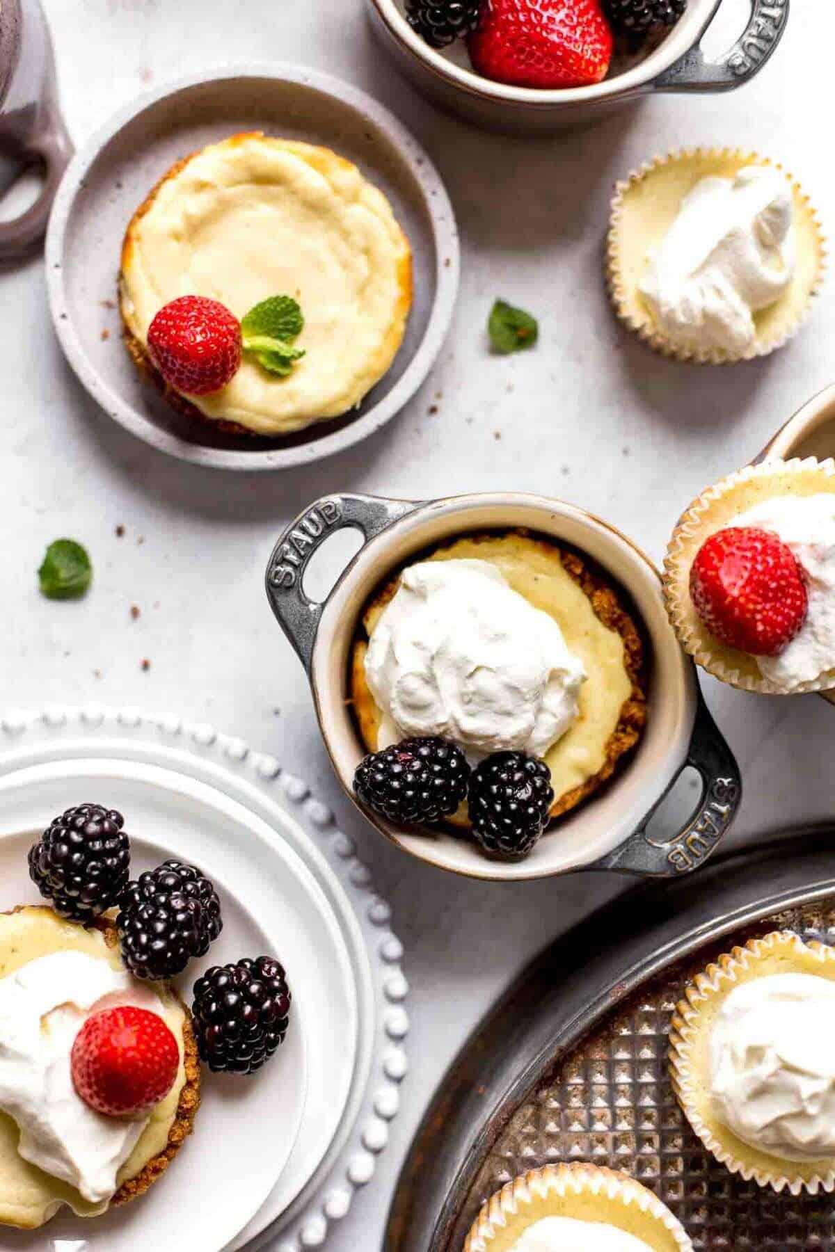 half dozen baked mini cheesecakes in ramekins and on serving plates