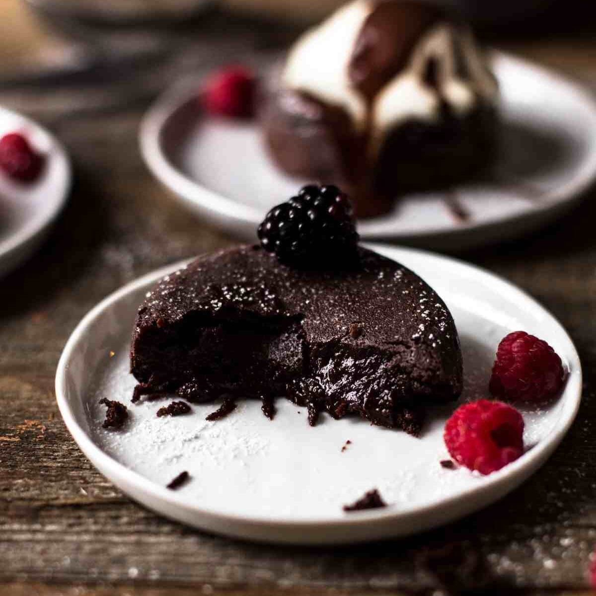 half eaten lava cake with gooey chocolate center oozing out of the center on a plate