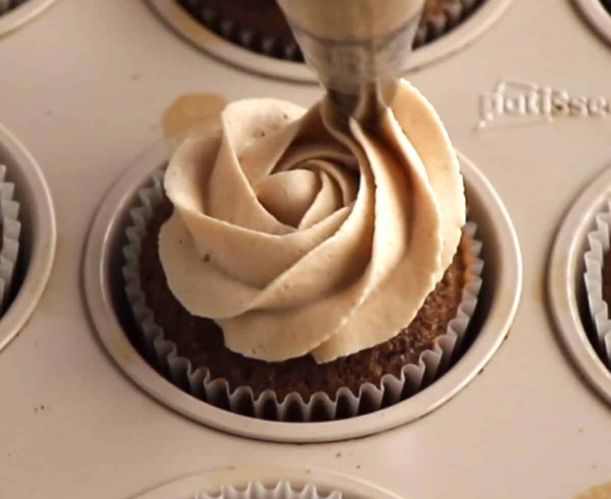 piping mascarpone frosting on top of cupcake