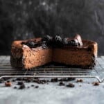 baked chocolate cheesecake on a wire rack with one quarter missing