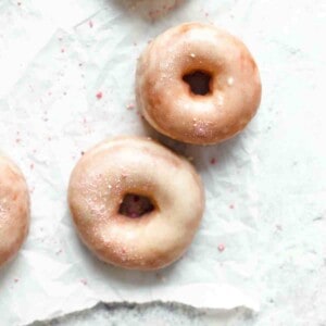 Three glazed doughnuts on white paper
