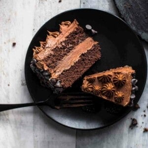 two slices of chocolate cake on a black serving plate with a fork
