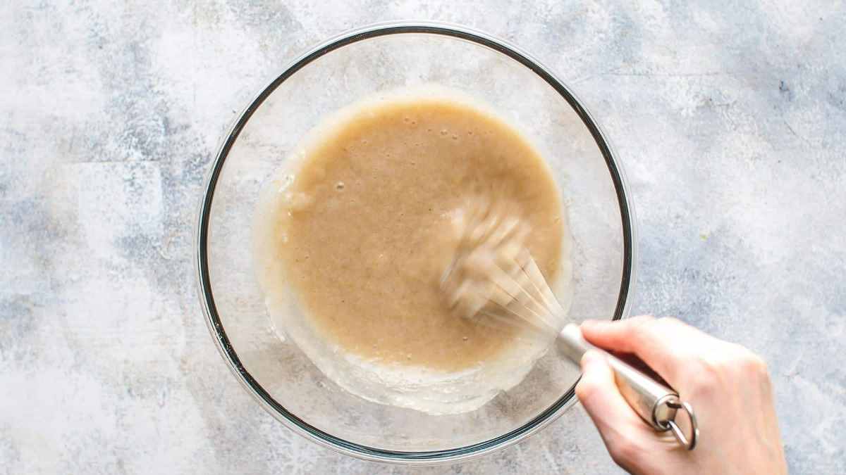 Whisking mashed bananas and sugar in large mixing bowl