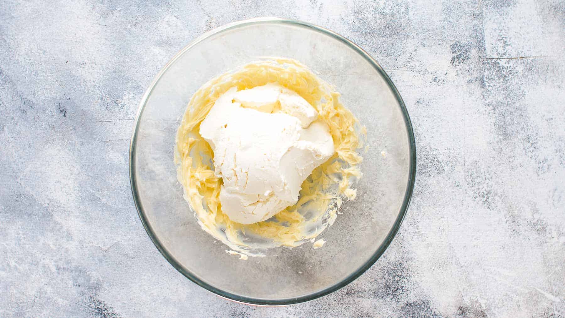 a dollop of mascarpone on top of mixed butter in a mixing bowl