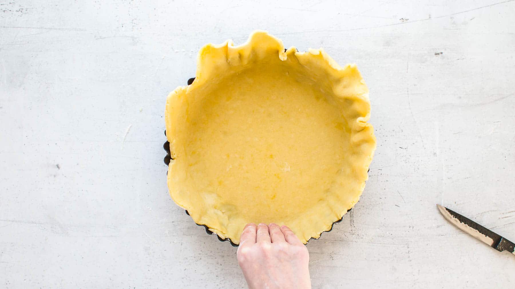 Pressing raw pie crust into a baking pan