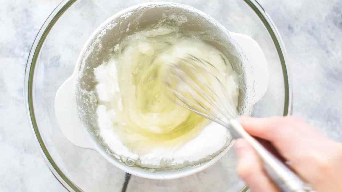 whisking egg whites, sugar, and cream of tartar in a bowl over a pot of boiling water