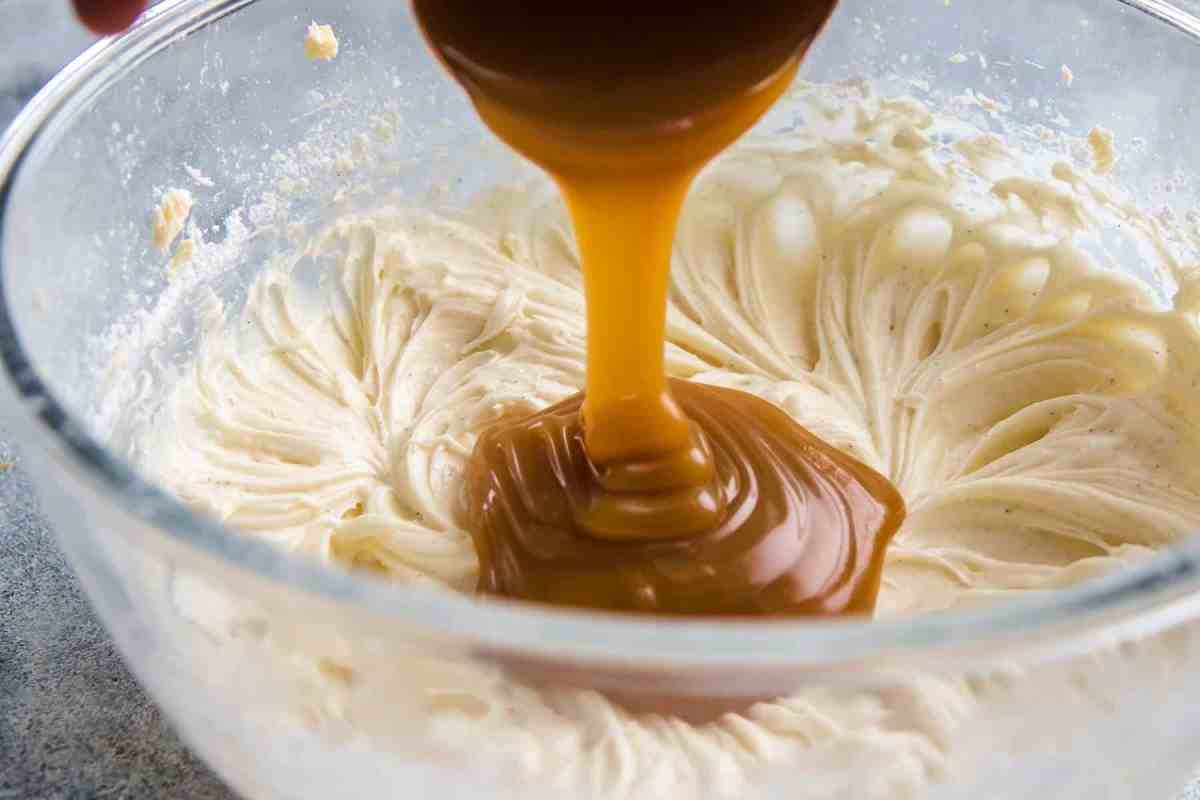 Pouring homemade caramel sauce to cream cheese frosting
