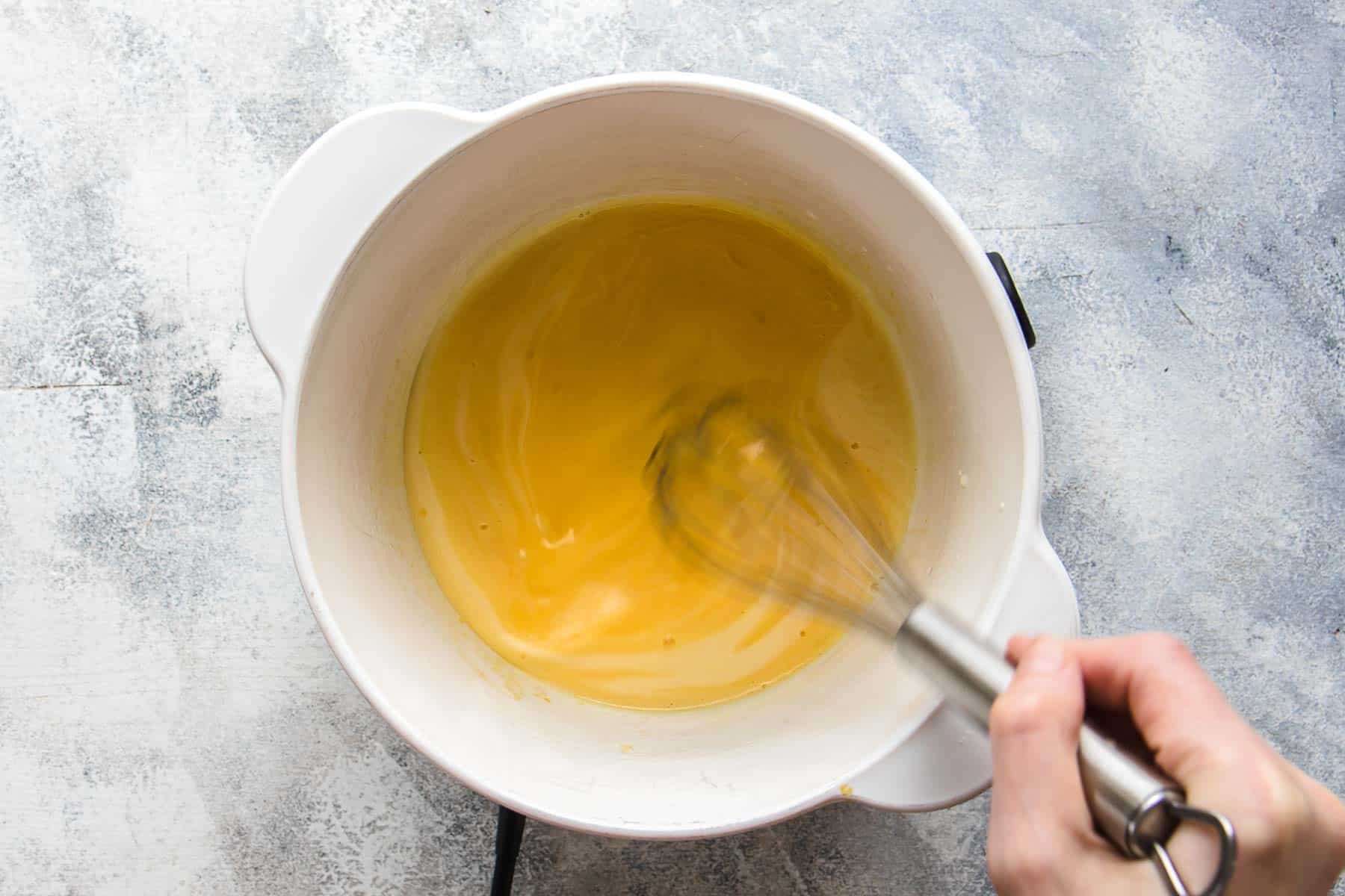 Cooking egg yolks, heavy cream, and sugar in a large white pot over heat