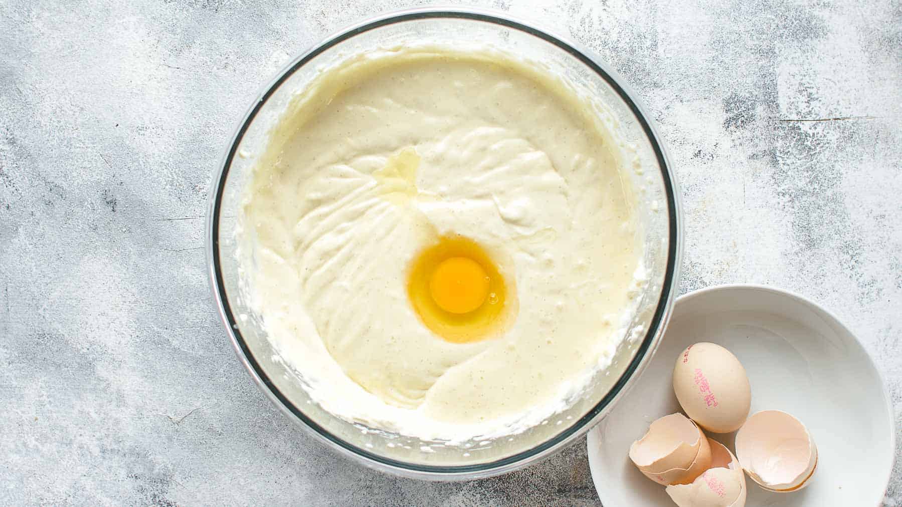 Adding the third egg to the coconut cheesecake batter