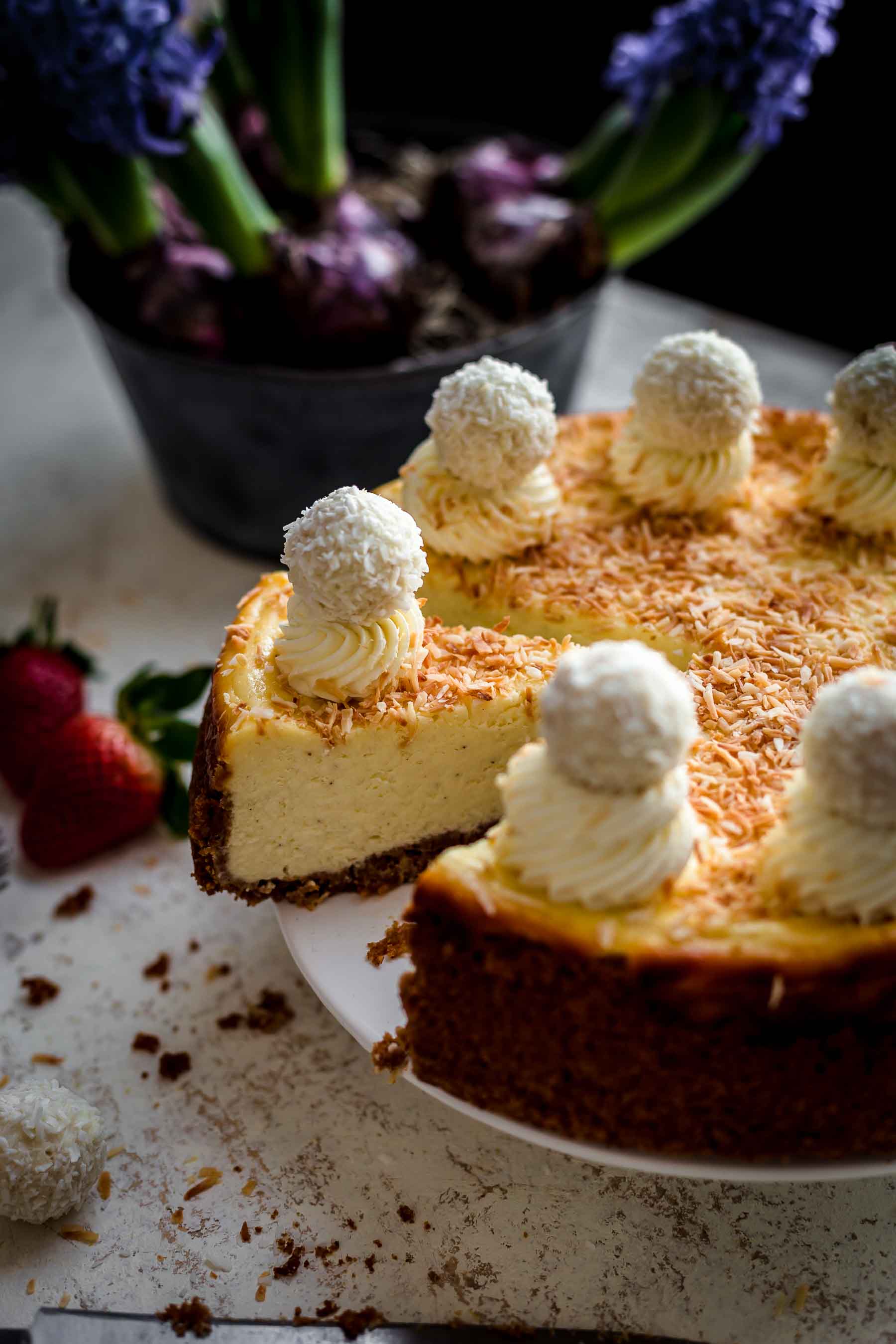 sliced cheesecake on serving plate with whipped cream and coconut decoration