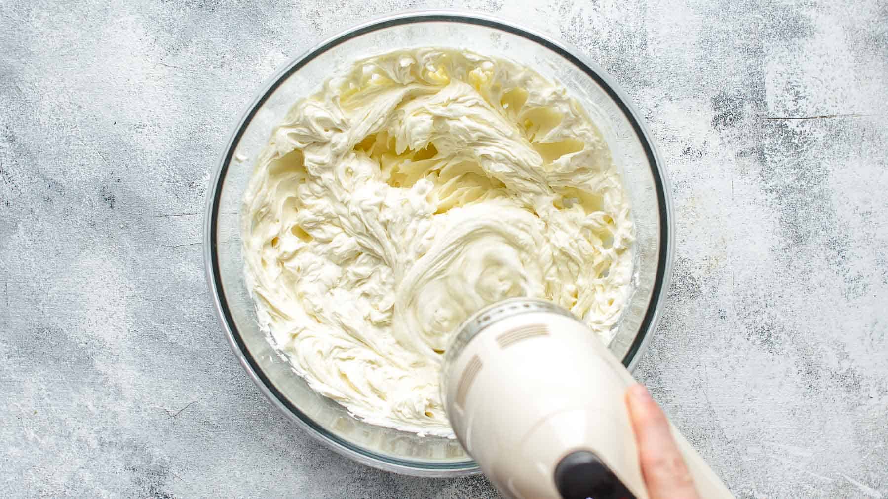 Mixing cream cheese, flour, and sugar in a large mixing bowl